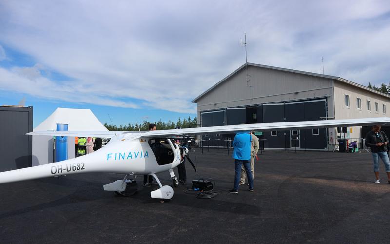 Pienkone, joka seisoo asfaltilla. Taustalla iso teollisuushalli.