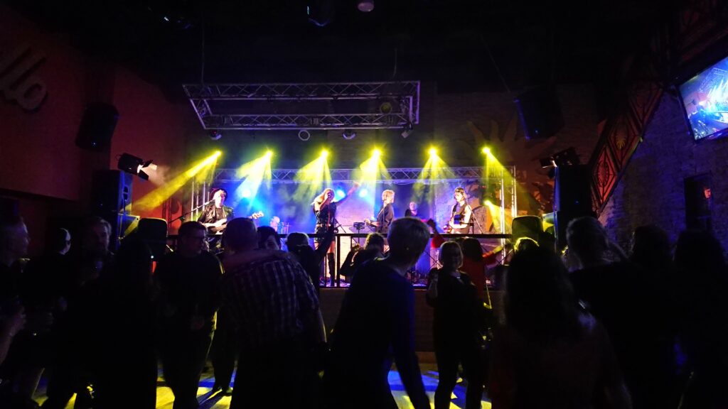 Musiikkikeikka pimeässä tilassa, värivalot osoittavat lavalle.