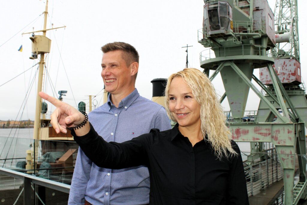 Nainen ja mies Kotkan kantasamassa nosturin edessä.