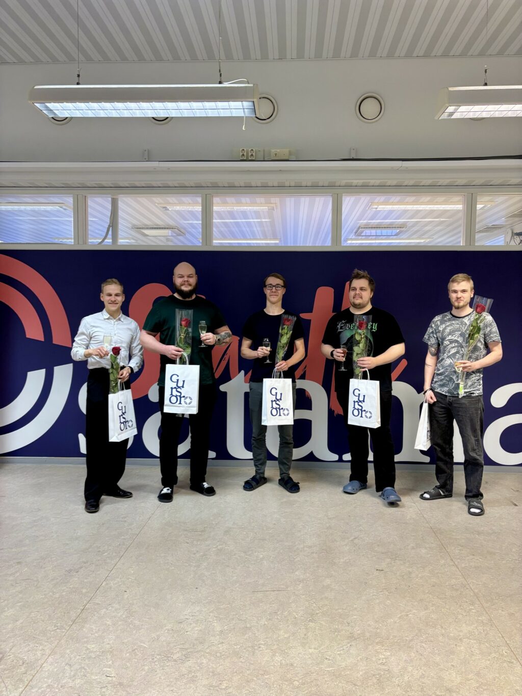 Normogamesin yrittäjät starttisataman tiloissa. Kuvassa juhlitaan valmistujaisia. Yrittäjillä on kädessään ruusut ja Cursorin paperikassit.