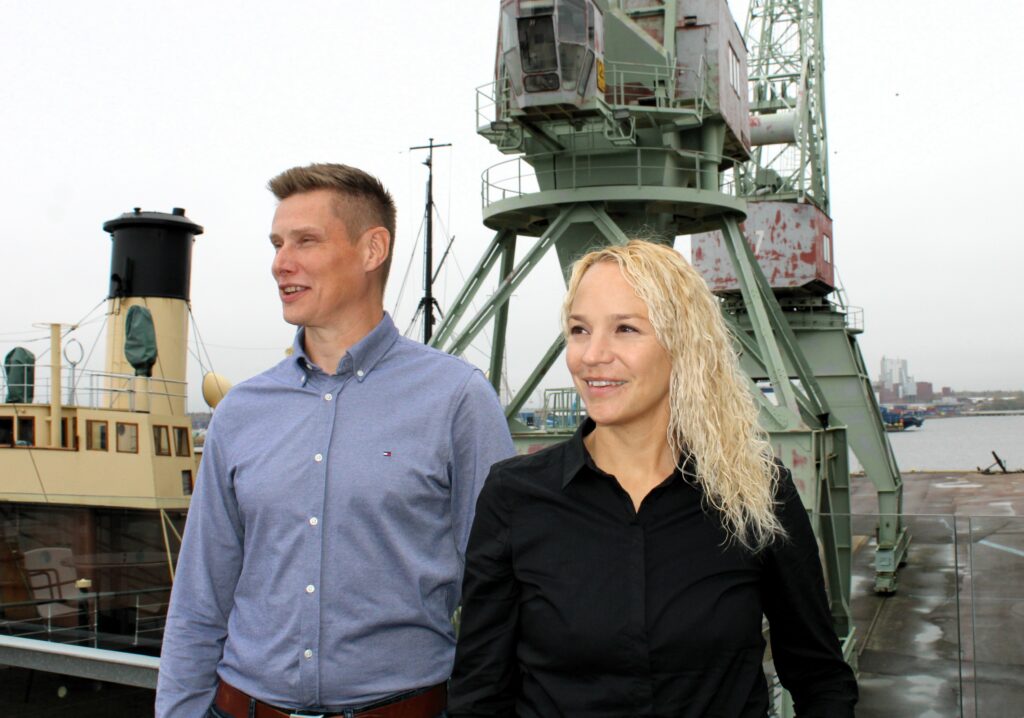 Nainen ja mies Kotkan kantasamassa nosturin edessä.